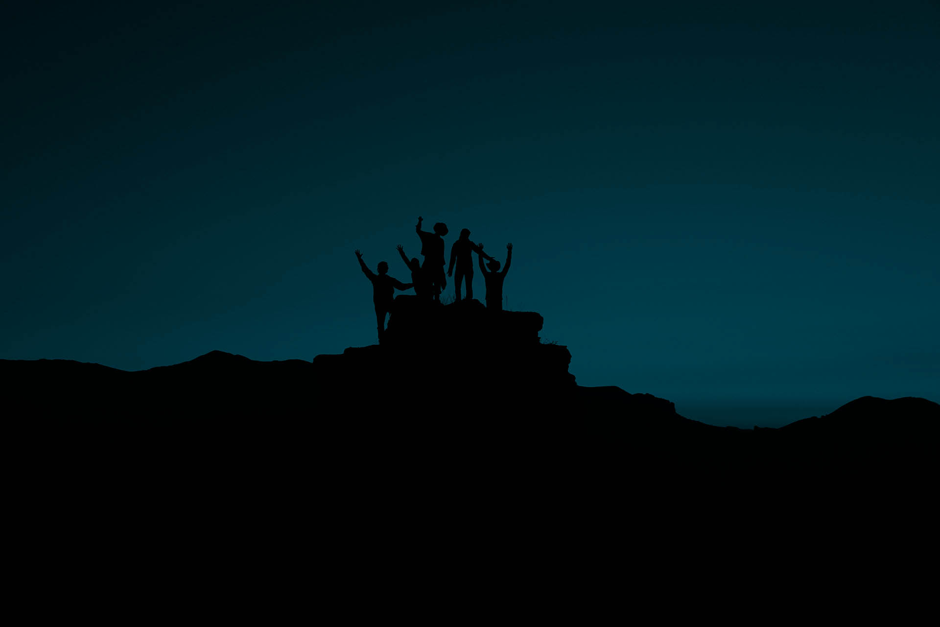 A group of people standing on a hill, that look like they are celebrating.